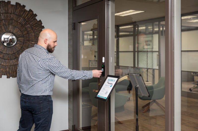 A bald white man with a beard holds a key fob up to the door to gain access to the 20Fathoms office.